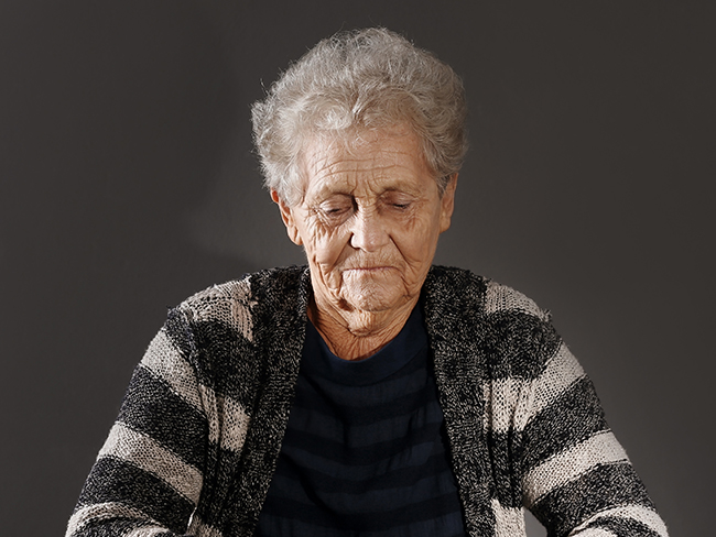 Elderly woman staring down at table